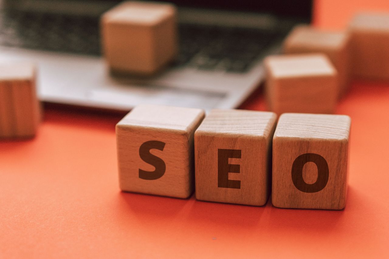 Des blocs en bois formant SEO sur un clavier d’ordinateur illustrent des notions de marketing numérique.